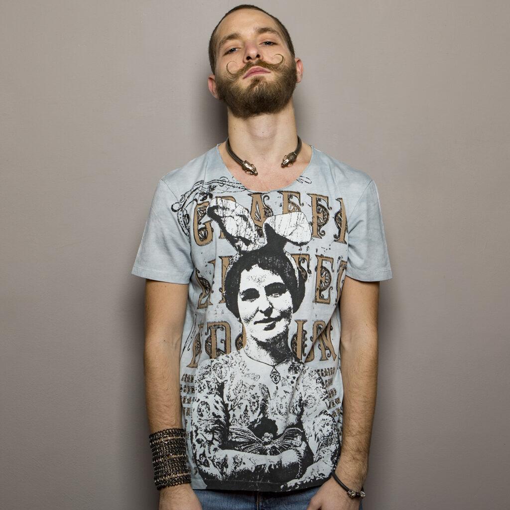 T-shirt with an artistic print depicting a woman with smiling rabbit ears in black and white with a bow on her head. The background of the graphic is decorated with stylised letters in a vintage design.