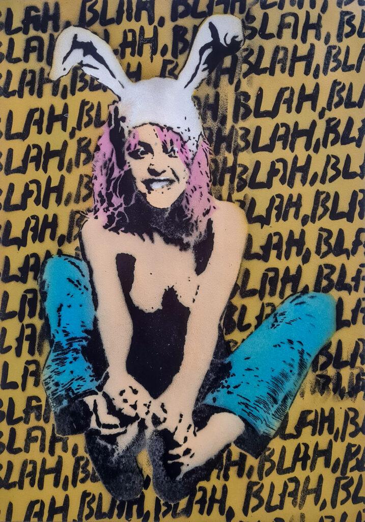 A hand-painted poster by White Rabbit featuring the "Flying Bunny" with a white rabbit hat, pink hair, blue jeans, and bare feet, sitting against a yellow background filled with repeated "BLAH BLAH BLAH" text in black.